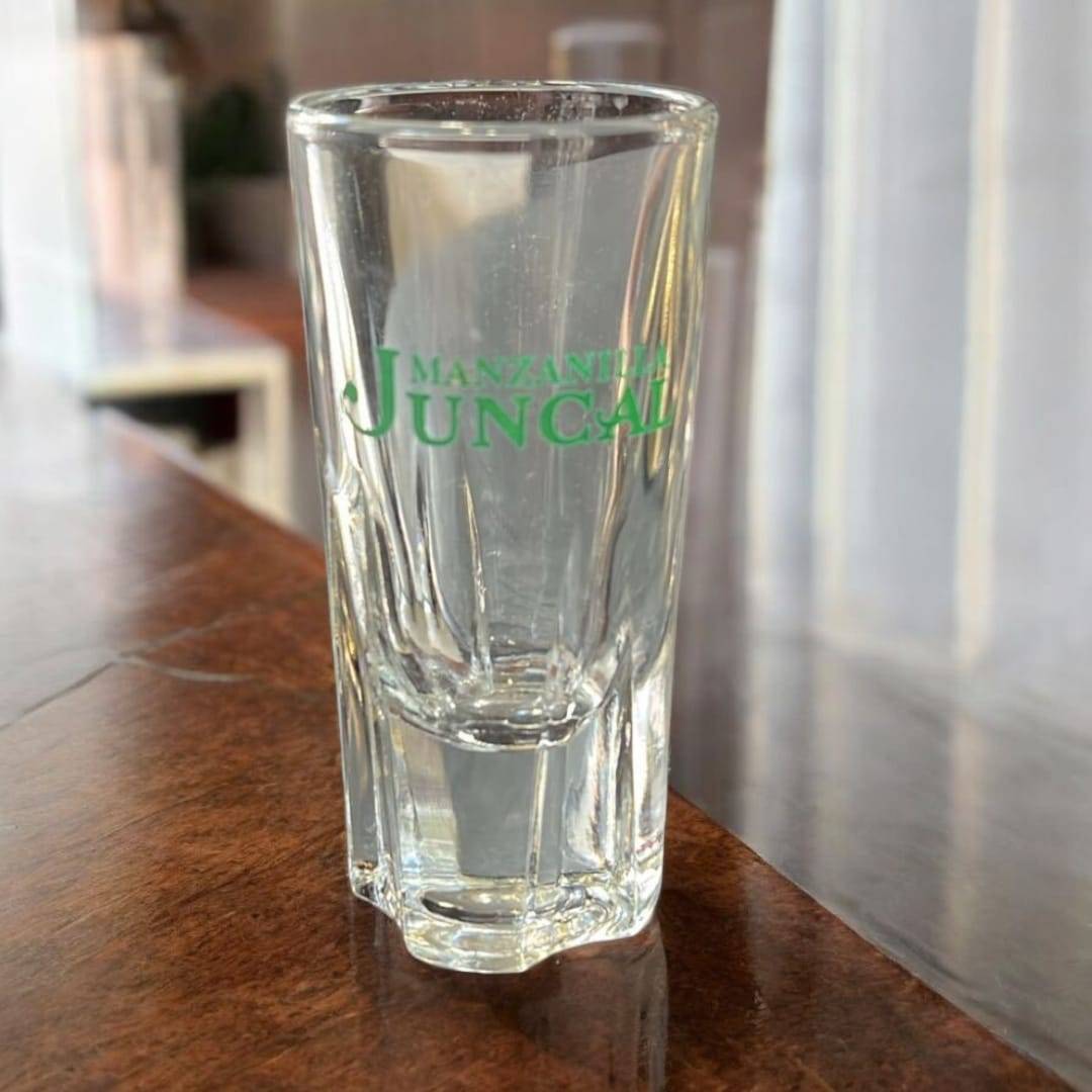 Vaso de cristal con logo verde Manzanita Juncal, parte del set cañero vintage dorado. Perfecto para coleccionistas de decoración clásica.