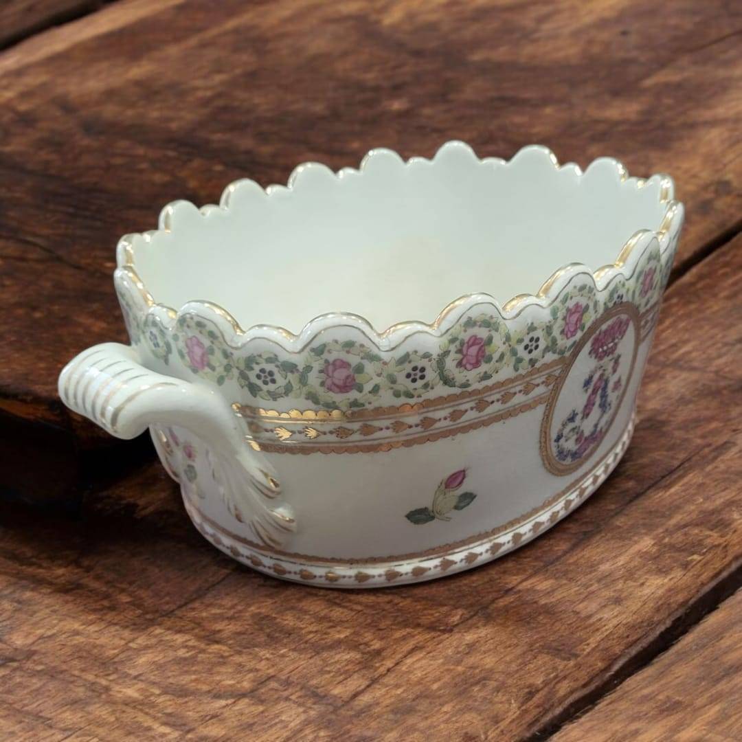 Decoración de porcelana con asas ornamentadas y borde ondulado, centro de mesa pintado a mano y firmado, estilo vintage refinado.