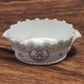 Centro de mesa de porcelana con diseño floral y borde ondulado, pintado a mano y firmado, ideal para decoración de interiores.
