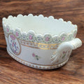 Vista lateral del centro de mesa de porcelana con asas decorativas, flores pintadas a mano y detalles dorados, pieza única de decoración.