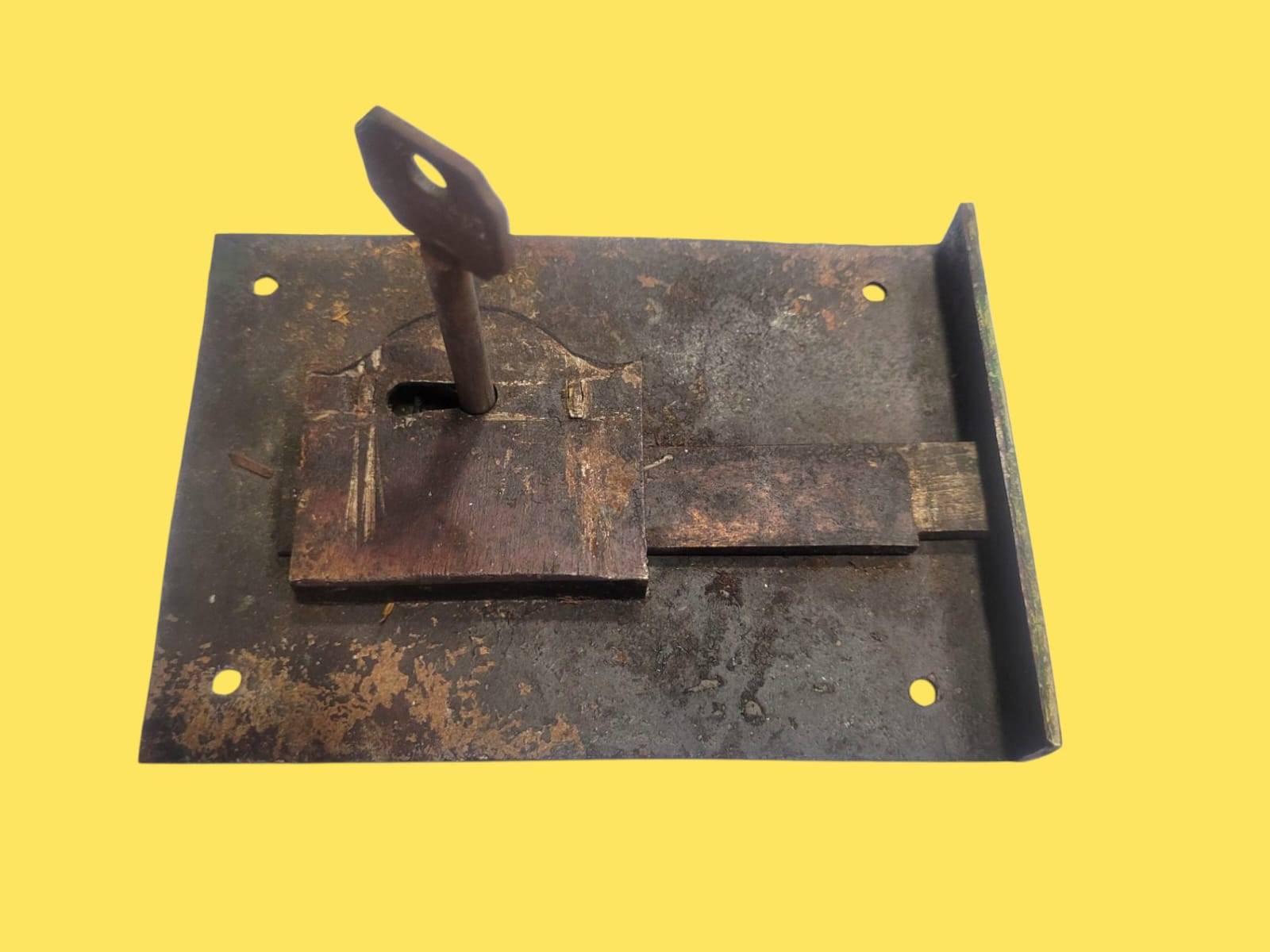 Cerradura antigua forjada a mano con llave insertada, mostrando mecanismo funcional. Pieza decorativa única para estilo vintage.