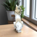 Chihuahua de Lladró captado de espaldas junto a una ventana, sobre fondo neutro.