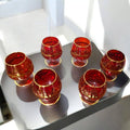 Juego de 6 copas de cristal Murano rojo con detalles dorados en una mesa moderna. Un toque de exclusividad para celebraciones y reuniones elegantes.