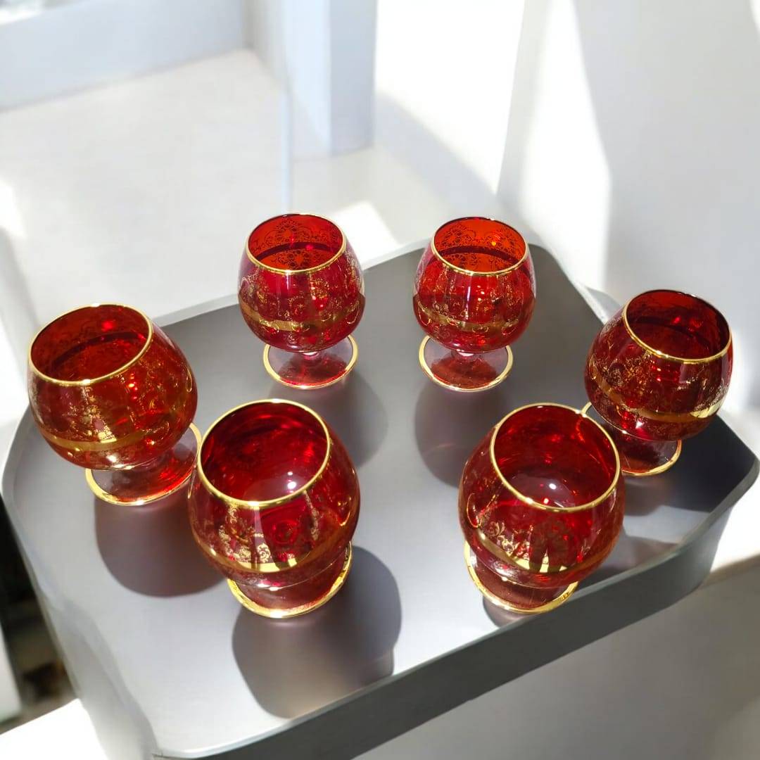 Juego de 6 copas de cristal Murano rojo con detalles dorados en una mesa moderna. Un toque de exclusividad para celebraciones y reuniones elegantes.
