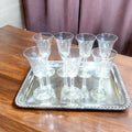 Copas de cristal tallado dispuestas en bandeja decorativa. Lote de 7 copas de licor con diseño fino y envío gratis incluido.