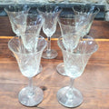 Copas de cristal de Bohemia talladas dispuestas en círculo sobre mesa rústica. Perfectas para decoración vintage y clásica.