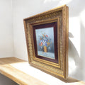 Pintura floral en óleo sobre lienzo con marco dorado, iluminada por la luz natural. Arte decorativo refinado para embellecer interiores con estilo.