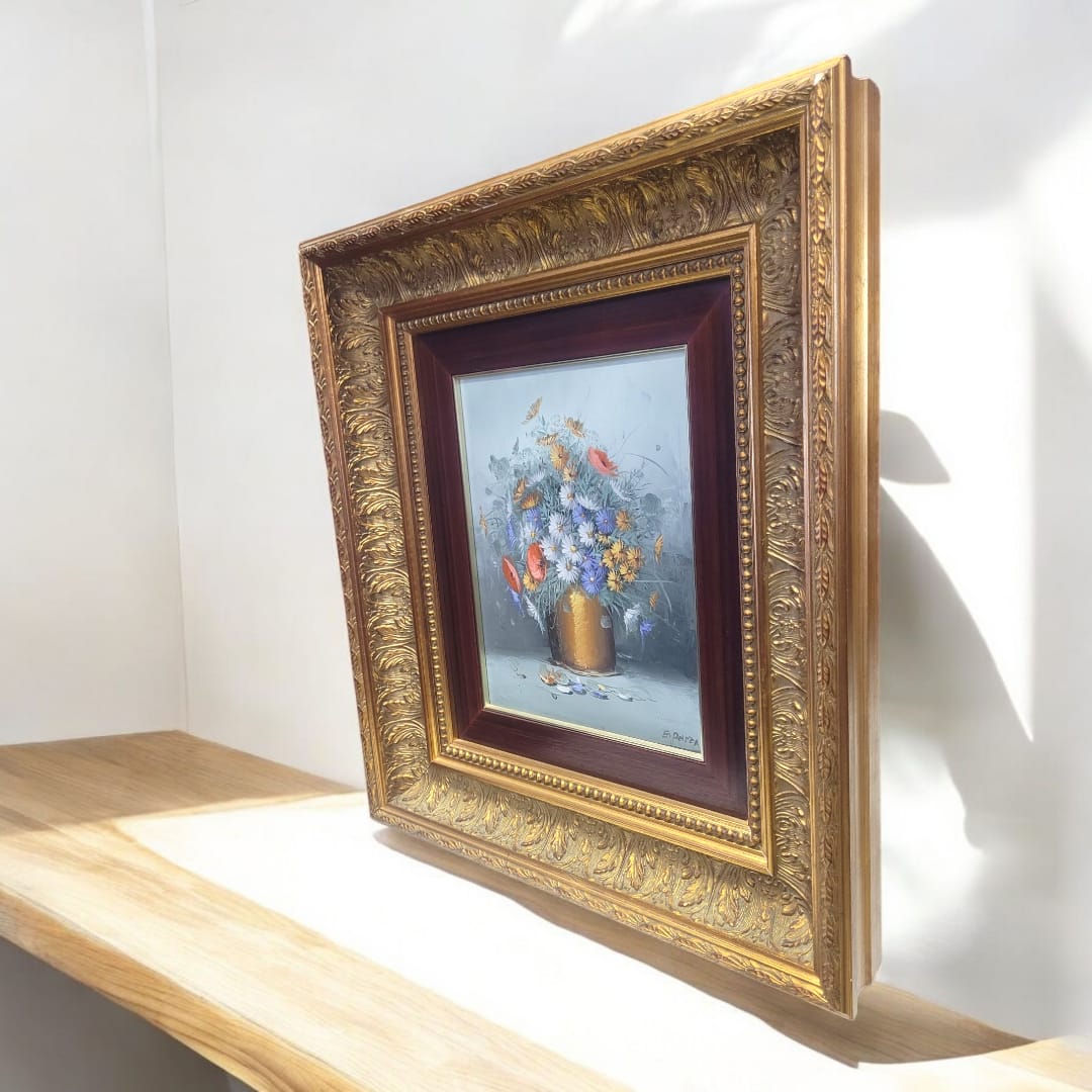 Pintura floral en óleo sobre lienzo con marco dorado, iluminada por la luz natural. Arte decorativo refinado para embellecer interiores con estilo.