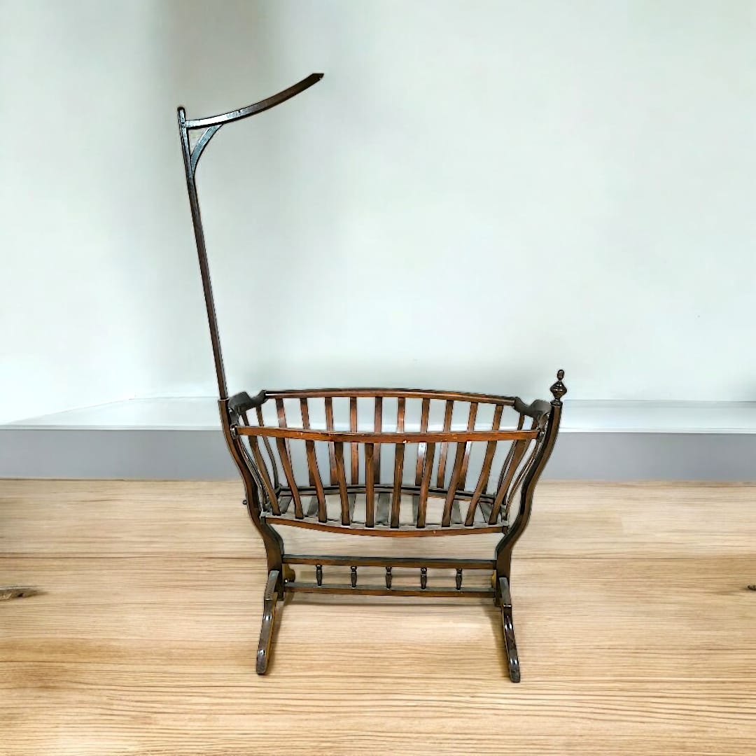 Cuna mecedora histórica estilo Art Nouveau, fabricada en Viena con madera oscura y diseño floral curvo.