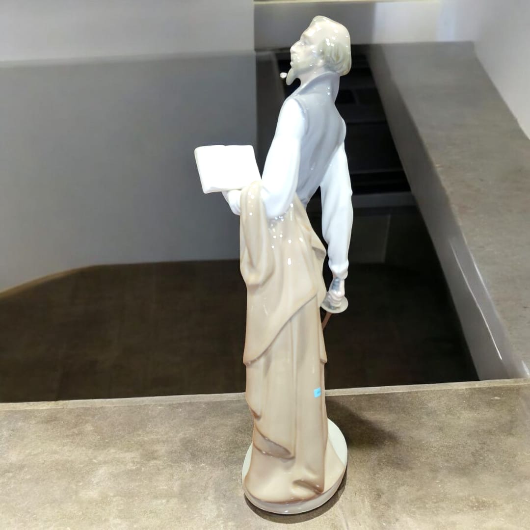 Escultura de porcelana NAO LLADRÓ representando a Don Quijote de la Mancha con libro en mano. Pieza decorativa exclusiva para coleccionistas.