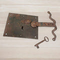 Cerradura antigua de hierro con llave incluida y detalles decorativos curvos. Accesorio decorativo para ambientes de estilo rústico y vintage.