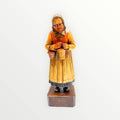 Figura de mujer mayor tallada en madera con vestido rústico y canastas, ideal para decoración vintage y coleccionistas de artesanía europea.