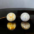 Esferas de mármol macizo decorativas para tu hogar con vetas naturales en tonos beige y blanco, sobre superficie negra brillante.