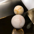 Esferas de mármol macizo decorativas para tu hogar apiladas sobre mesa dorada, con acabado brillante y diseño sofisticado.