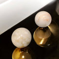Esferas de mármol macizo decorativas para tu hogar en tonos claros con vetas suaves, colocadas sobre mesa metálica dorada.