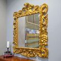 Espejo dorado isabelino del siglo XIX con talla en madera, marco ornamentado con penacho decorativo, ideal para decoración clásica de interiores.