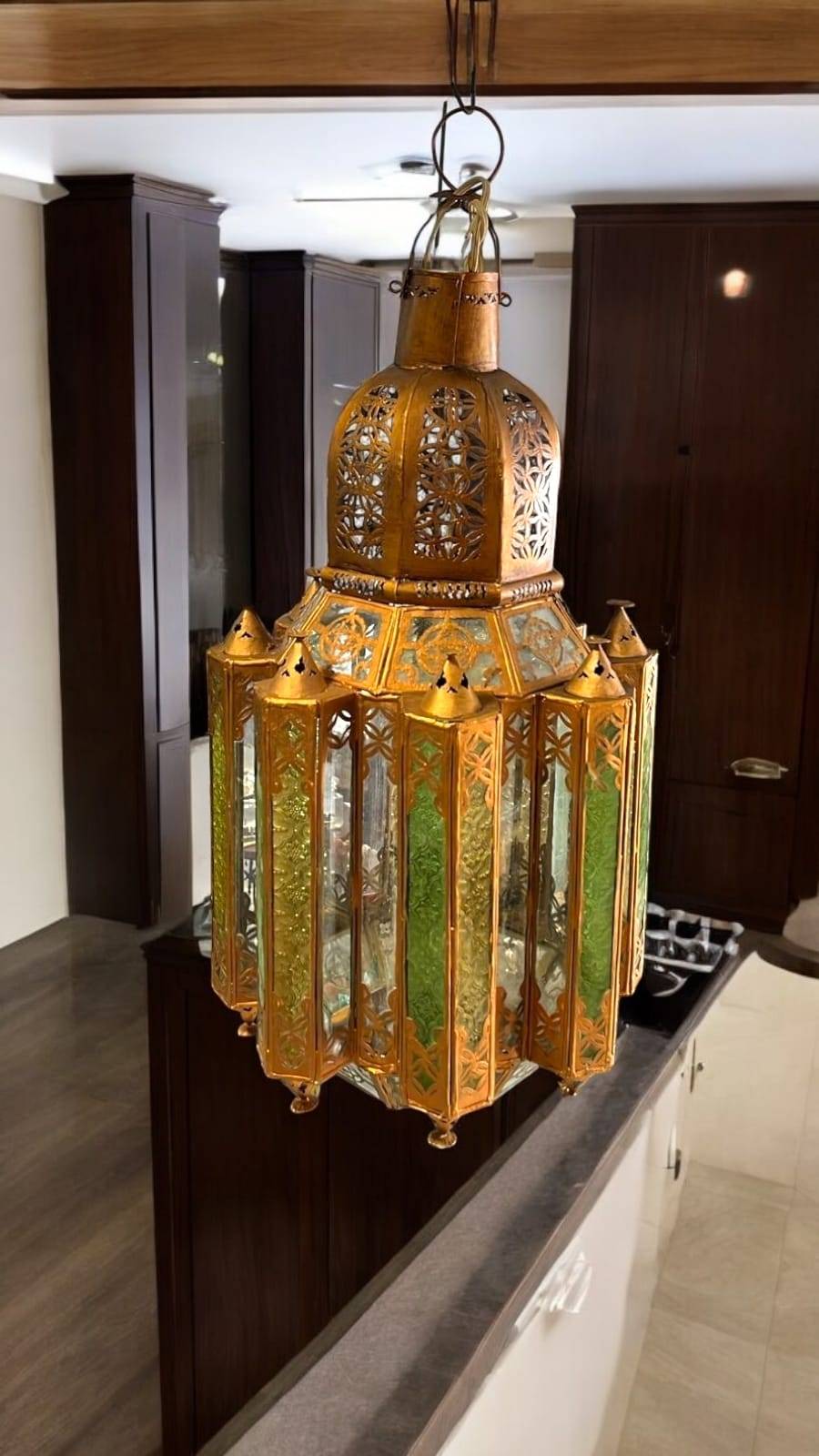 Farol musulmán colgante de metal dorado con paneles de cristal verde, ideal para decoración de interiores con estilo árabe en cocinas o salones.
