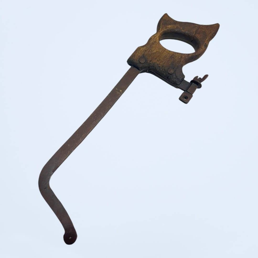 Sierra antigua sin hoja con estructura metálica oxidada y empuñadura de madera, perfecta para decoración nostálgica en el hogar o jardín.