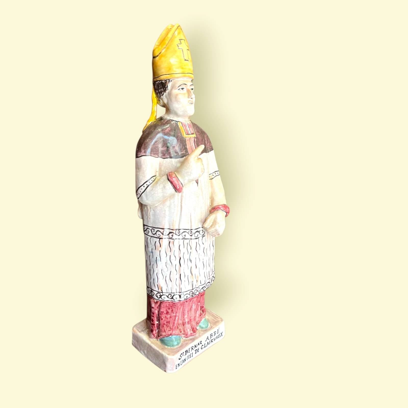 Figura de San Bernardo de Claraval en terracota esmaltada, con detalles simbólicos y acabado artesanal, perfecta para espacios espirituales.