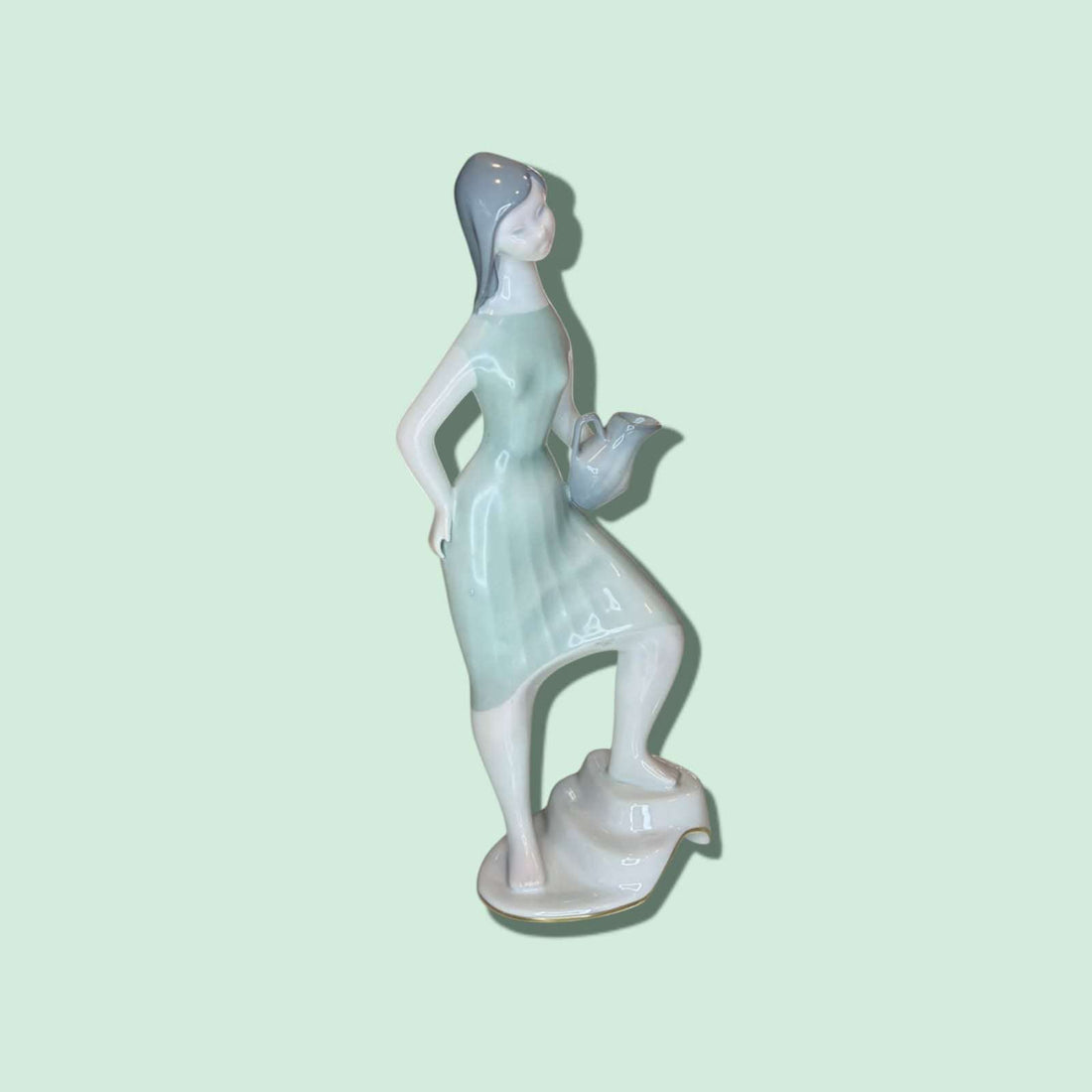 Esta exquisita Figura de porcelana, elaborada por la prestigiosa marca española Santa Clara, representa a una joven con un cántaro, interpretada en un estilo delicado, estilizado y lleno de movimiento. 