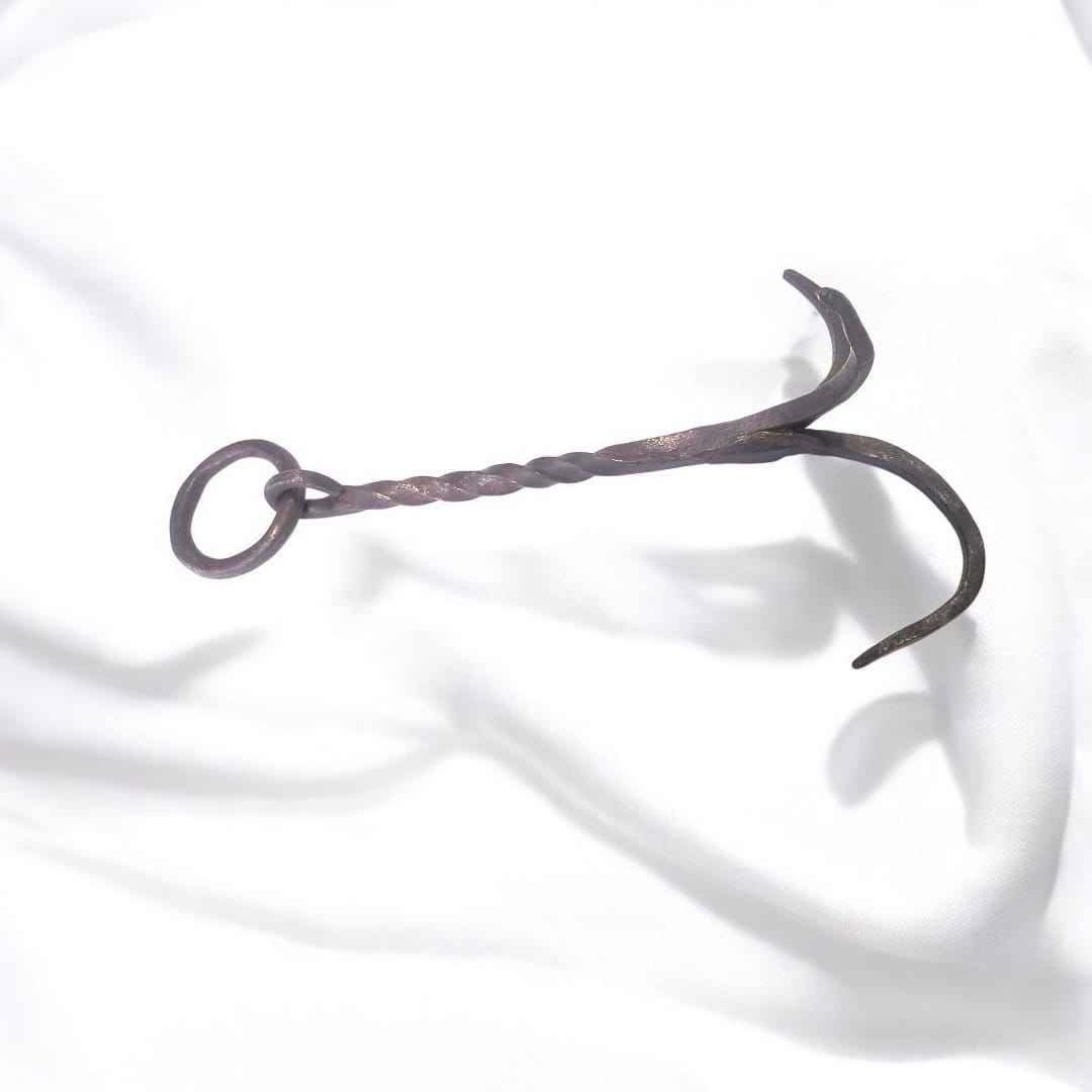 Su estructura presenta tres garras curvas afiladas y robustas que aseguran un agarre firme en diversas superficies.