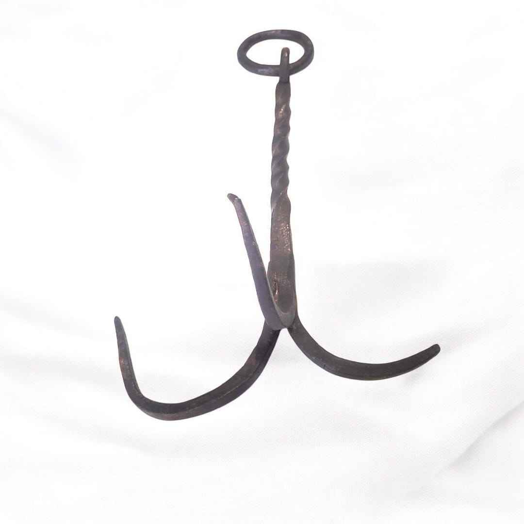 El gancho garabato de forja de tres patas es una pieza antigua forjada completamente a mano en hierro macizo, con un diseño que fusiona resistencia, técnica y arte utilitario.