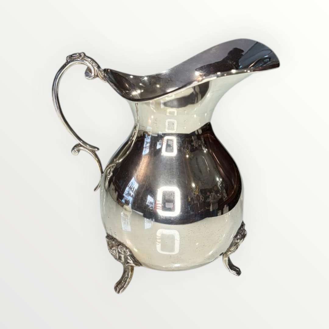 Jarra de metal plateado con diseño clásico y patas ornamentadas, ideal para decoración elegante en el hogar. Elegancia clásica y diseño intemporal.