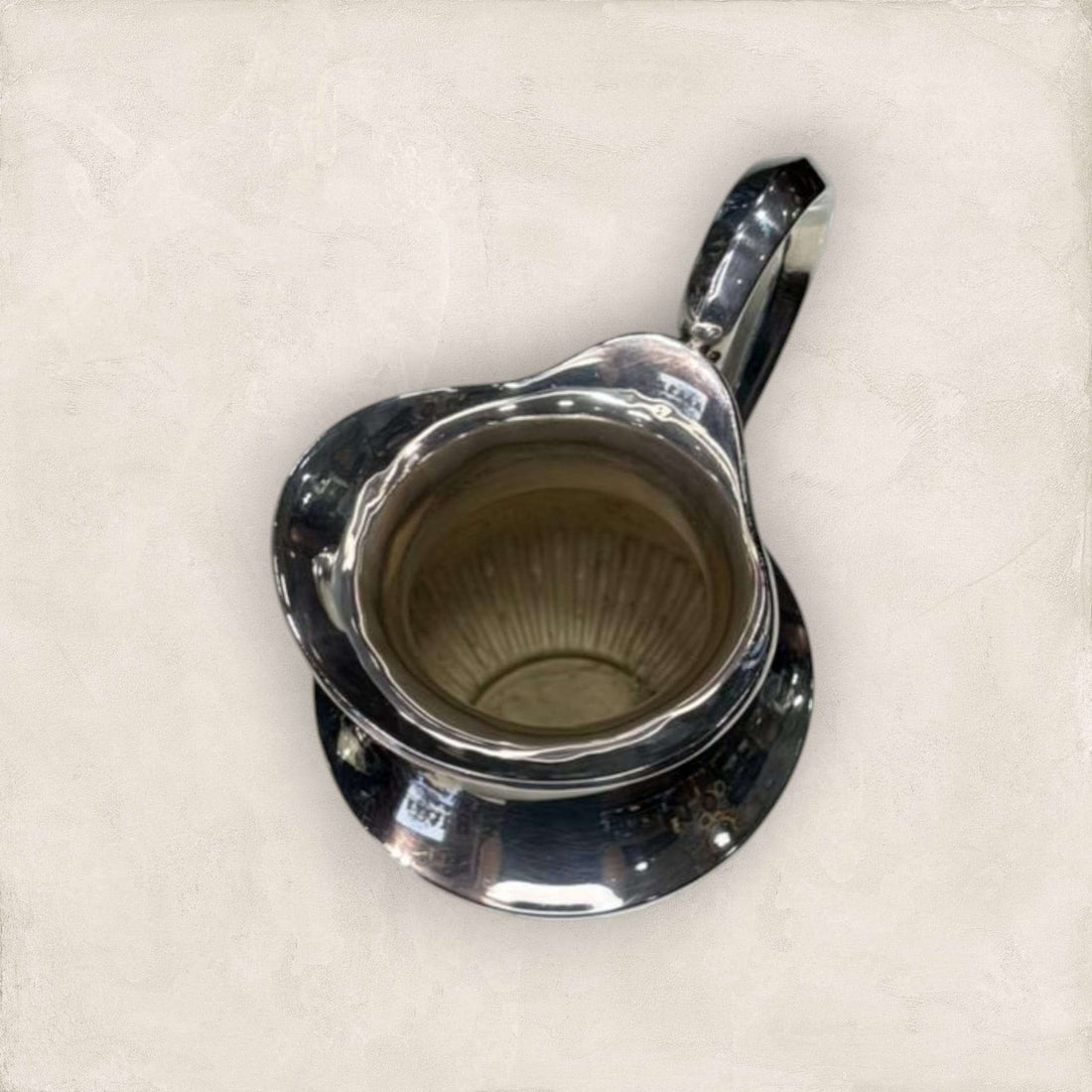 Jarra de metal plateado con acabado brillante y diseño curvo, ideal para decoración elegante en espacios del hogar.