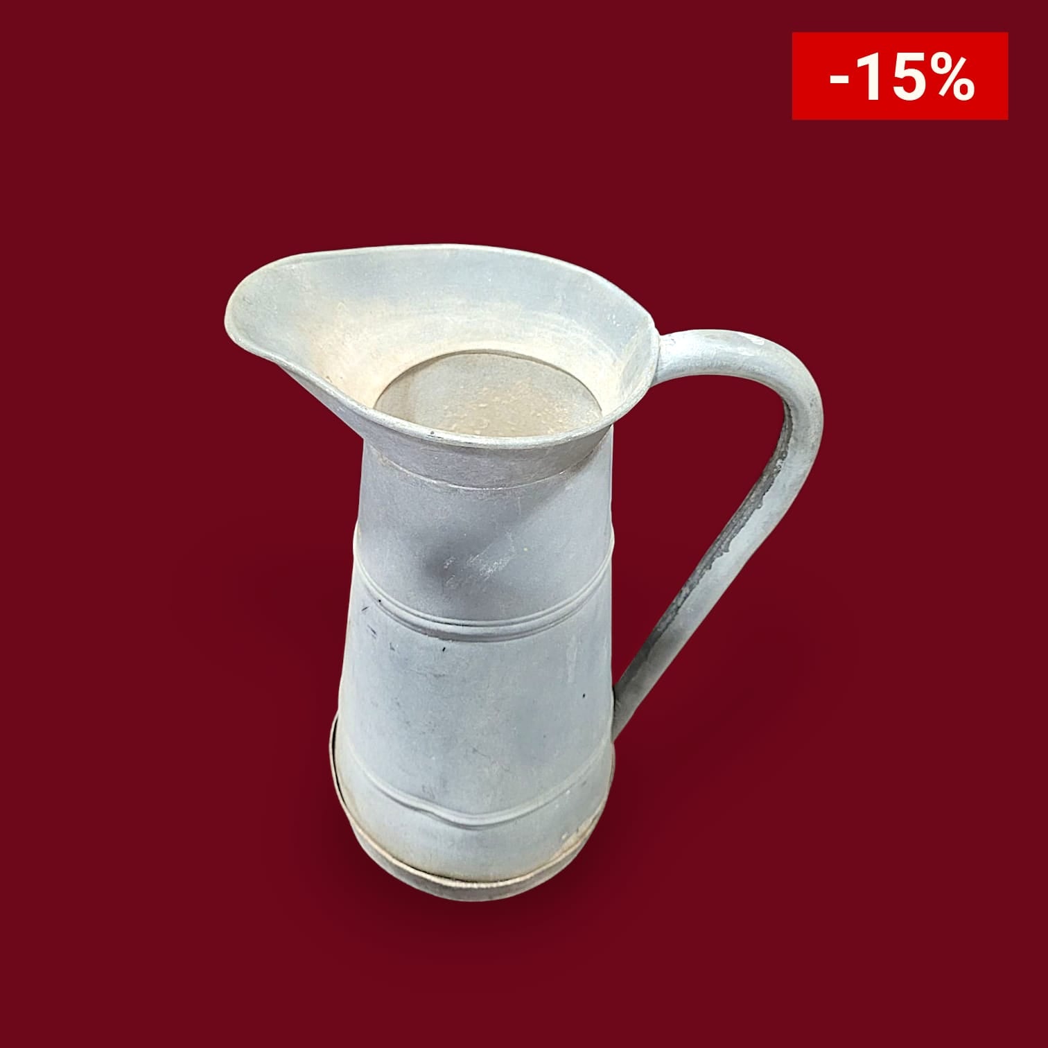 Jarra de aluminio con asa sirviendo agua fresca en un vaso .