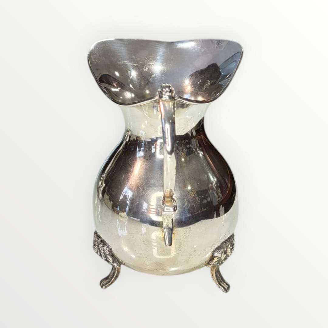 Jarra de metal plateado con diseño clásico y patas ornamentadas, ideal para decoración elegante en el hogar. Elegancia clásica y diseño intemporal.