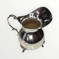 Jarra de metal plateado con diseño clásico y asa ornamentada, ideal para decoración elegante en el hogar. Pieza única de estilo intemporal.