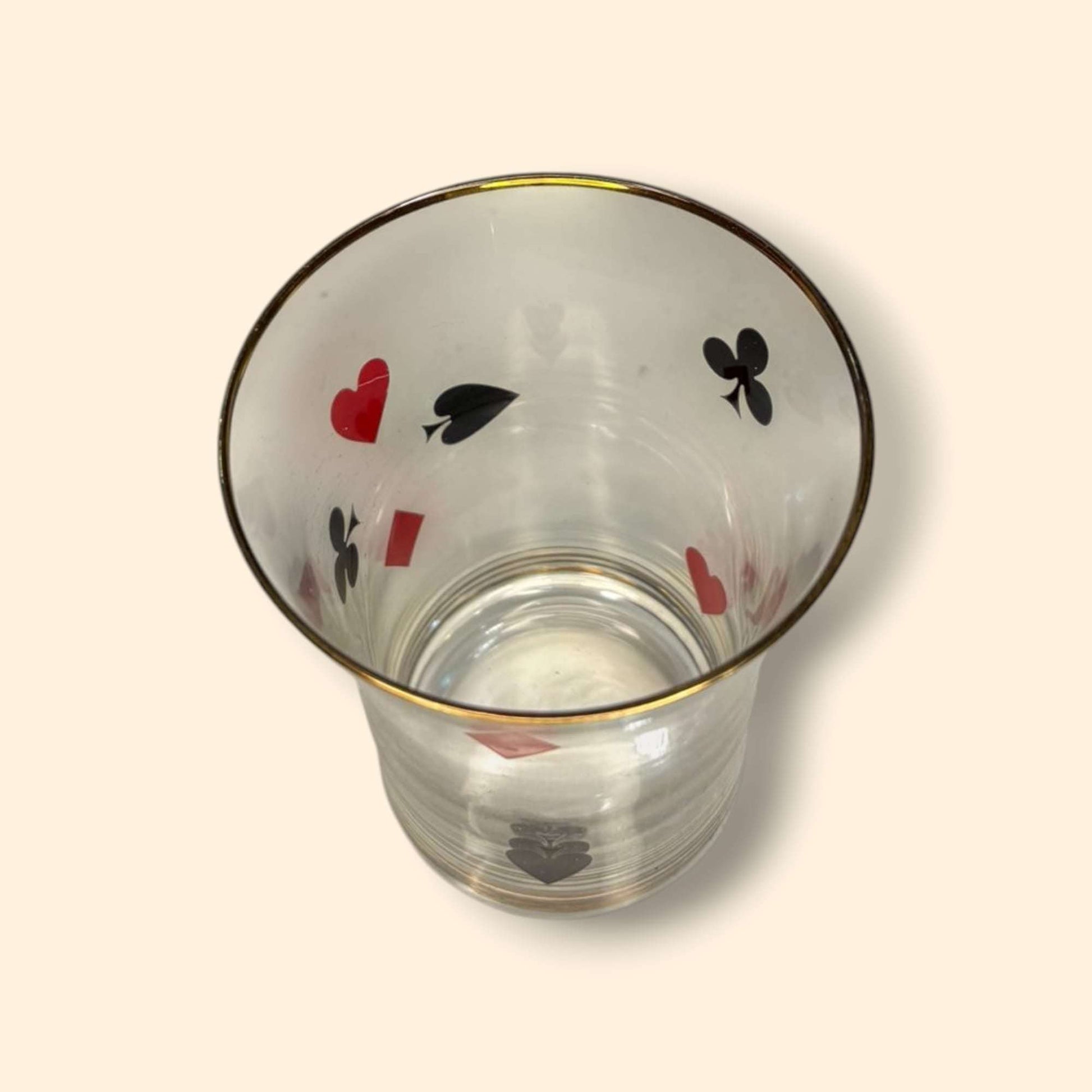 Vaso visto desde arriba con símbolos de baraja francesa y borde dorado, perteneciente al juego de jarra y vasos vintage de cristal.