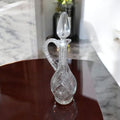 Jarra licorera de cristal tallada con diseño clásico y asa decorativa, ideal para complementar la decoración del hogar.