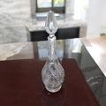 Jarra licorera de cristal tallada con diseño elegante y tapa en forma de gota, ideal para decoración o servir licores.