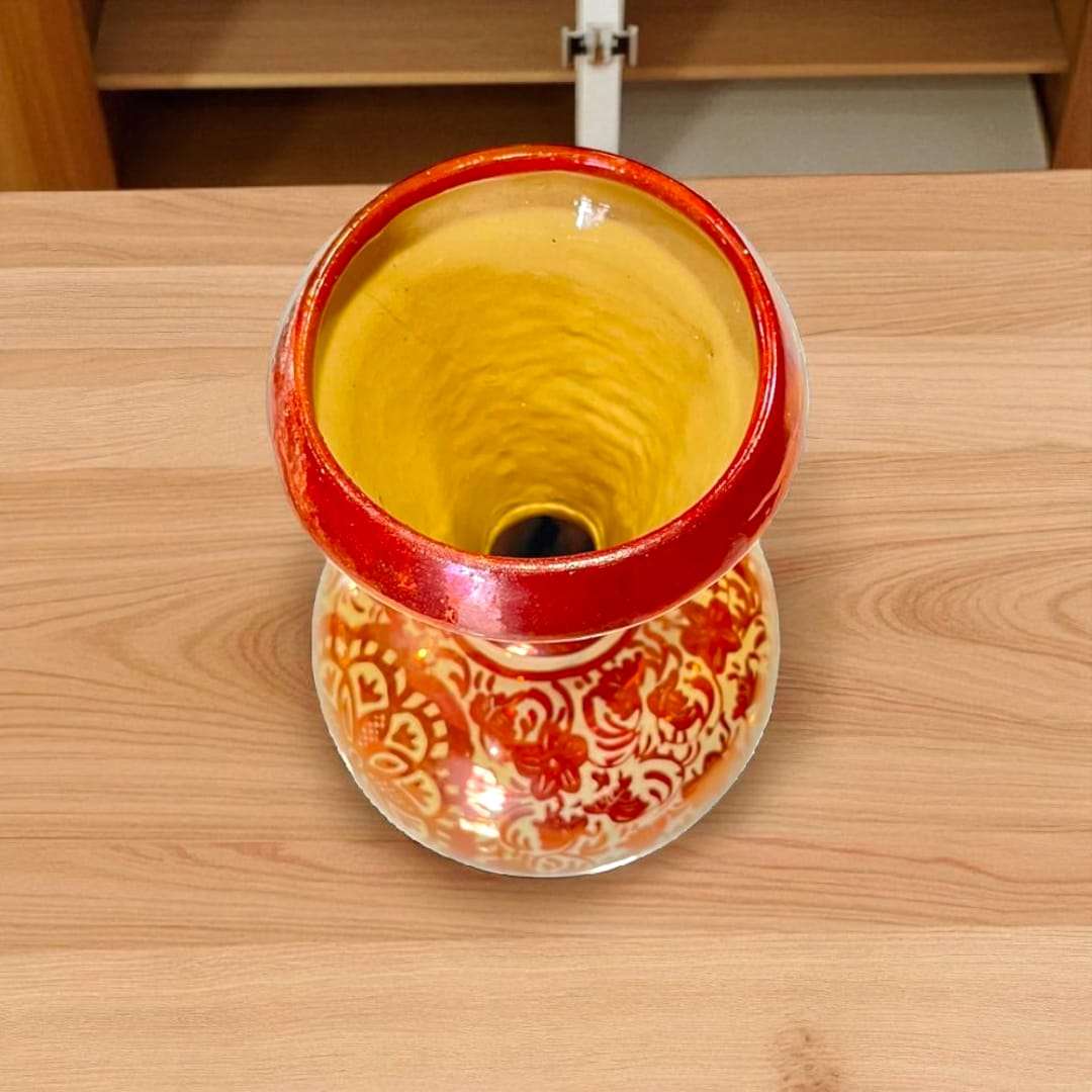 Jarrón de cerámica de Manises sobre mesa de madera, resaltando sus detalles pintados a mano.

P
