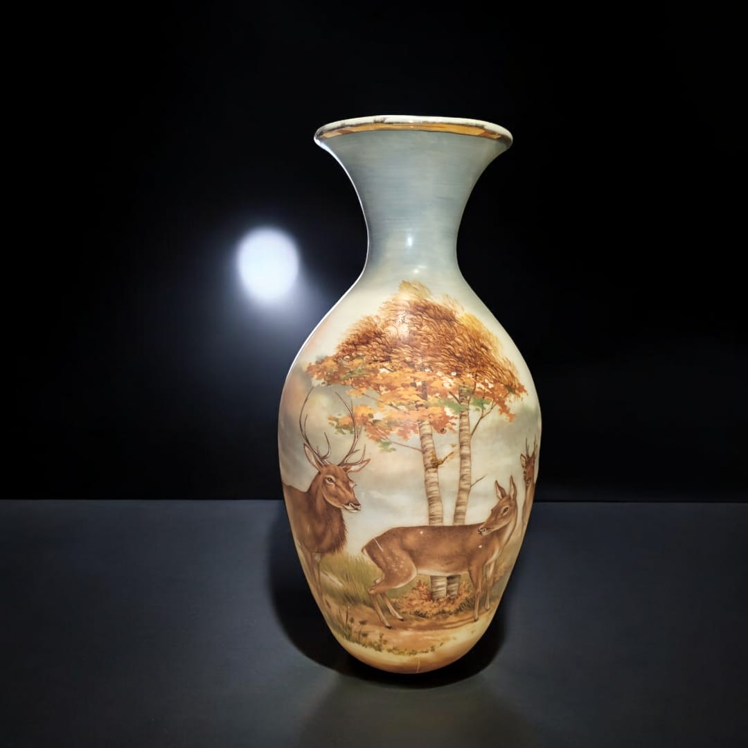 Jarrón de porcelana con diseño de ciervos bajo árboles en un paisaje natural, pintado a mano con filo dorado.