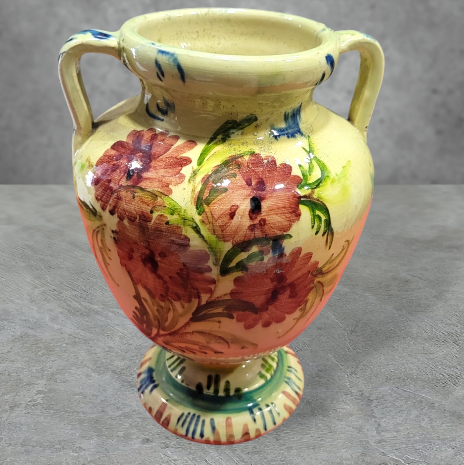Ánfora decorativa de cerámica esmaltada con flores pintadas a mano en colores vibrantes. Diseño artesanal exclusivo para embellecer interiores.