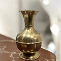 Jarrón de metal clásico con diseño vintage y acabado dorado, perfecto como florero o pieza decorativa para embellecer cualquier ambiente.