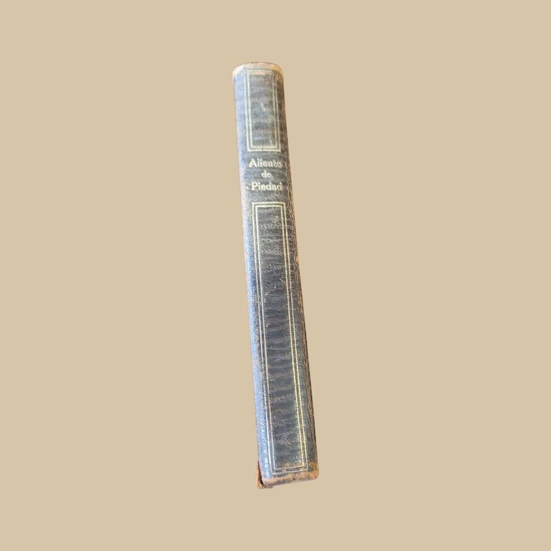Lomo del libro 'Aliento de Piedad' con letras doradas, edición antigua perfecta para coleccionistas de libros de oraciones religiosas únicos.