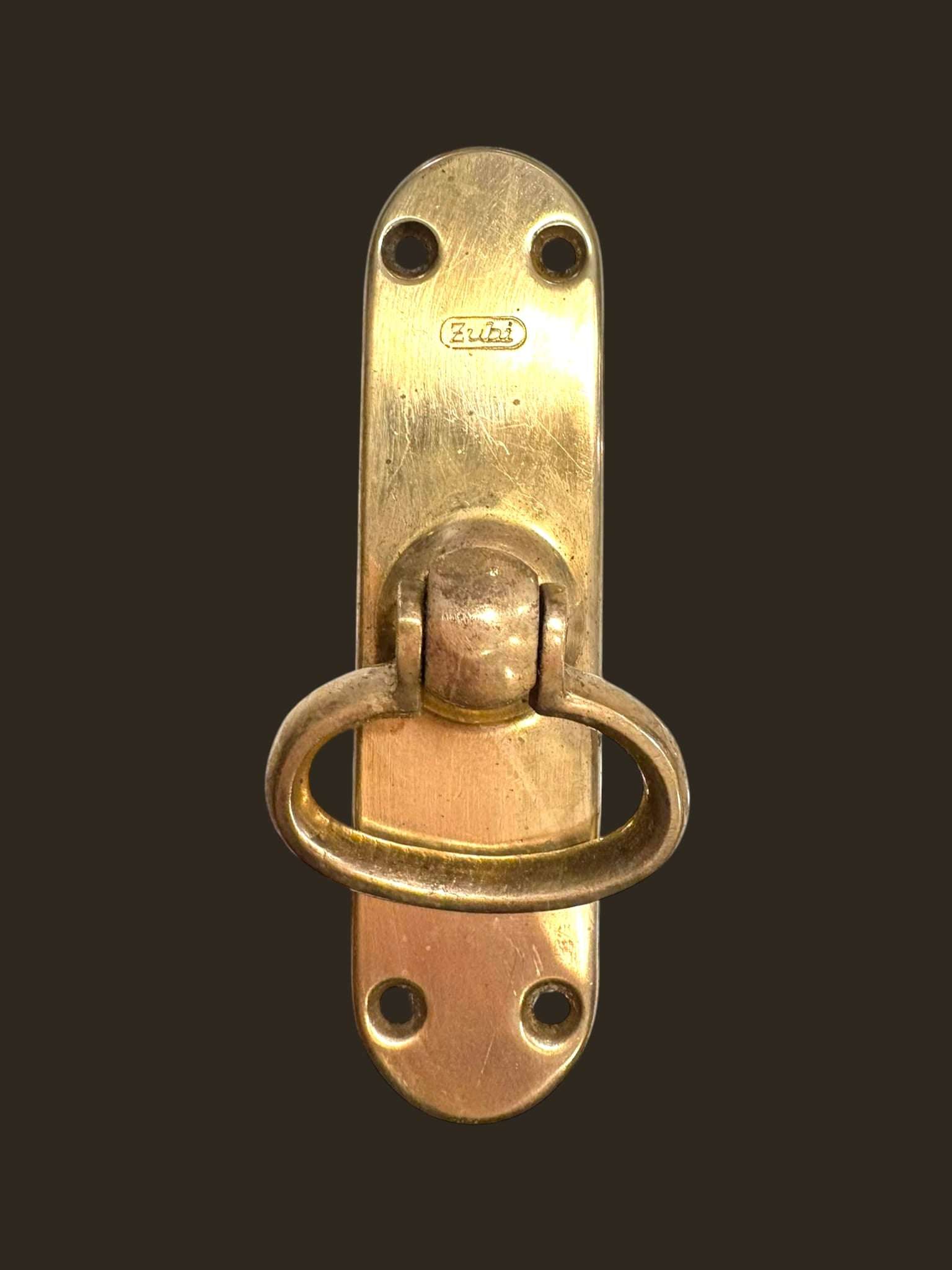 Fabricado íntegramente en metal dorado, presenta un sistema de anilla abatible con base rectangular, pensado para facilitar el cierre manual con firmeza.