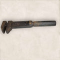 Llave inglesa antigua ajustable vista lateral con pátina metálica.
