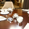 Azucarero de metal plateado con forma de manzana abierta sobre mesa elegante, perfecto para decoración de comedor y uso funcional en reuniones.