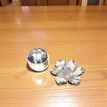 Azucarero de metal plateado con forma de manzana desmontado junto a base de hojas, ideal para decoración de cocina o comedor con estilo artesanal.