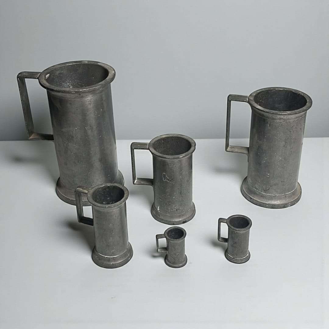 Conjunto de medidas metálicas antiguas sobre fondo gris neutro.