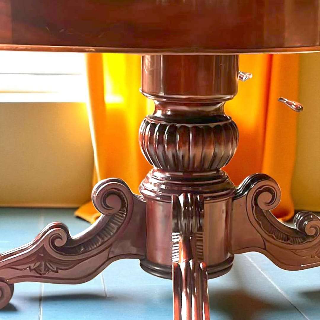 Primer plano de la base central tallada a mano de mesa comedor de caoba antigua, con detalles ornamentales y estilo clásico artesanal.
