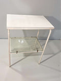 Mesa auxiliar blanca vintage con balda de cristal vista en ángulo frontal.