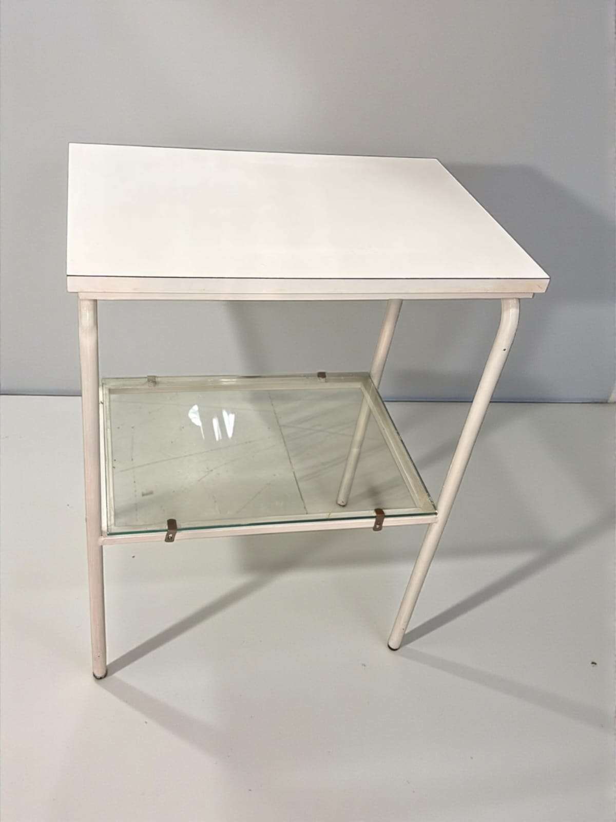 Mesa auxiliar blanca vintage con balda de cristal vista en ángulo frontal.