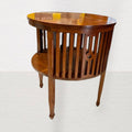 Fabricada con madera asiática maciza de alta densidad y veta visible, esta mesa destaca por su forma redonda, estructura reforzada con listones verticales ornamentales y un estante inferior que multiplica su funcionalidad.