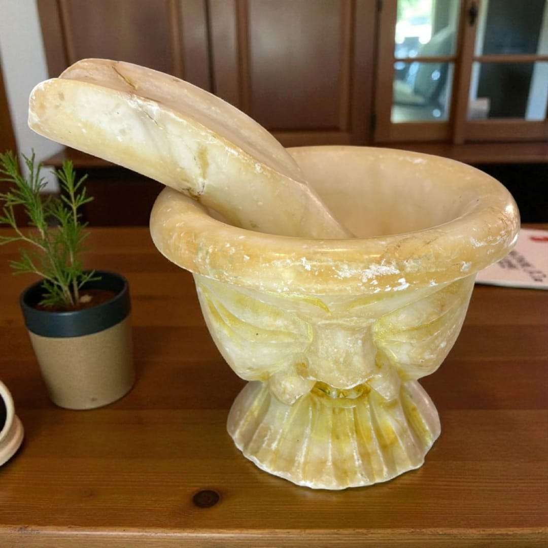 Mortero de alabastro tallado a mano con maja original, colocado sobre mesa de madera. Ideal para decoración de cocina estilo rústico.