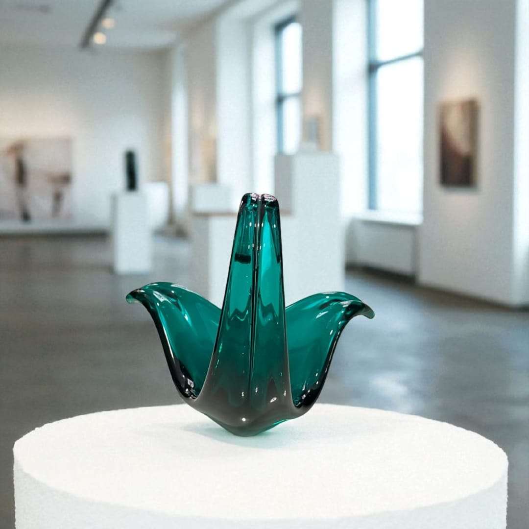 Pieza de Cristal Murano – Arte único para tu decoración en verde esmeralda con forma floral, expuesta sobre pedestal en galería de arte moderna.